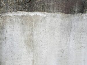 Detailed view of a rough, gray concrete wall, showcasing unique texture and stucco-like surface.